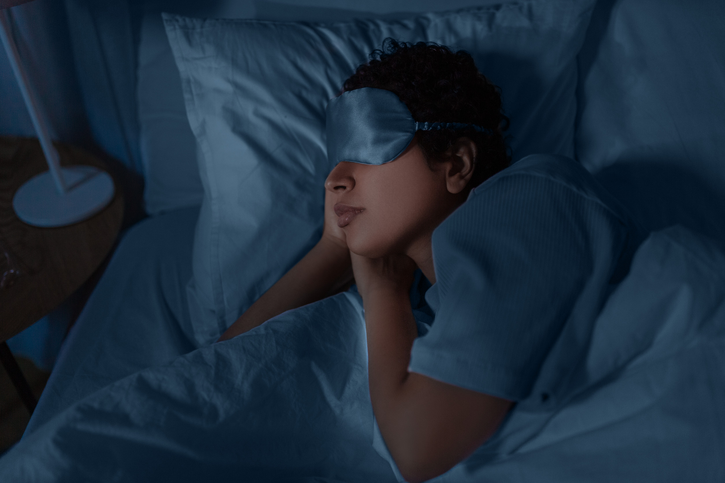 woman in eye mask sleeping in bed at home at night