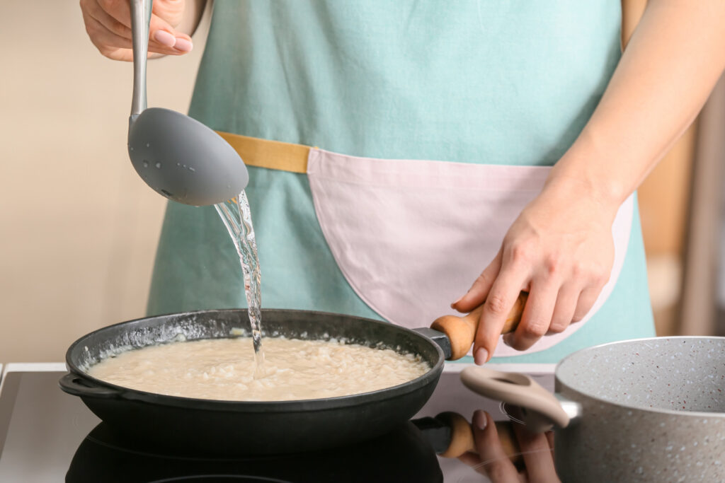 Woman cooking risotto in kitchen