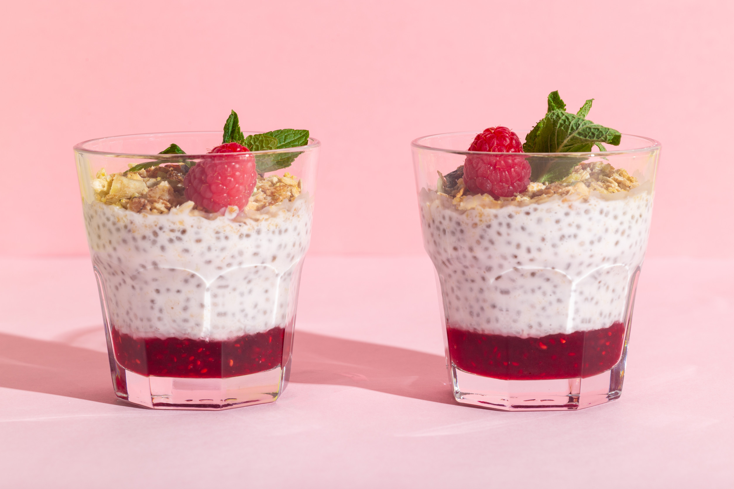 Chia seeds vanilla pudding with raspberry, oats musli and mint on rose hard shadow. High quality photo