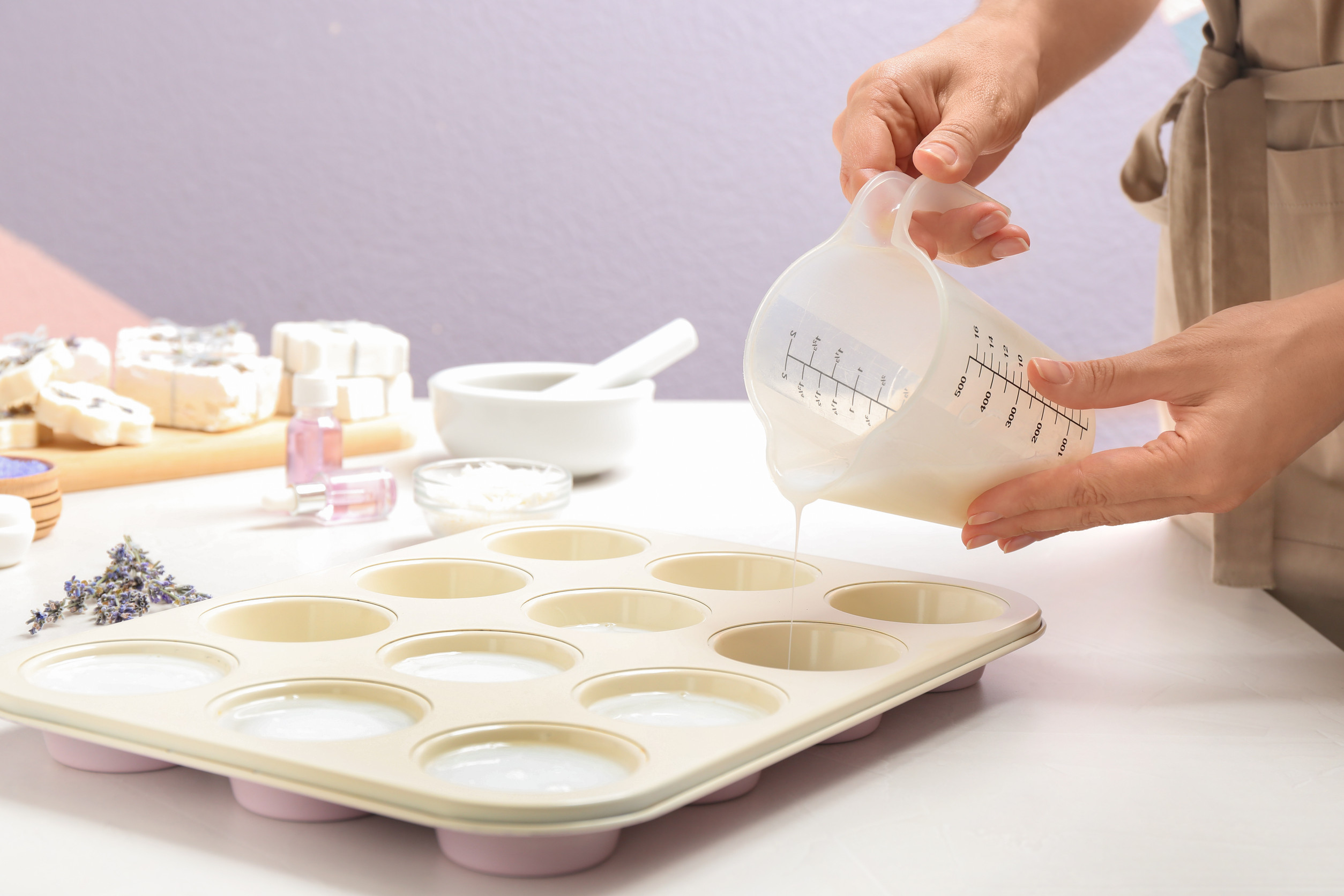Woman making hand made soap bar with lavender flowers at table, closeup