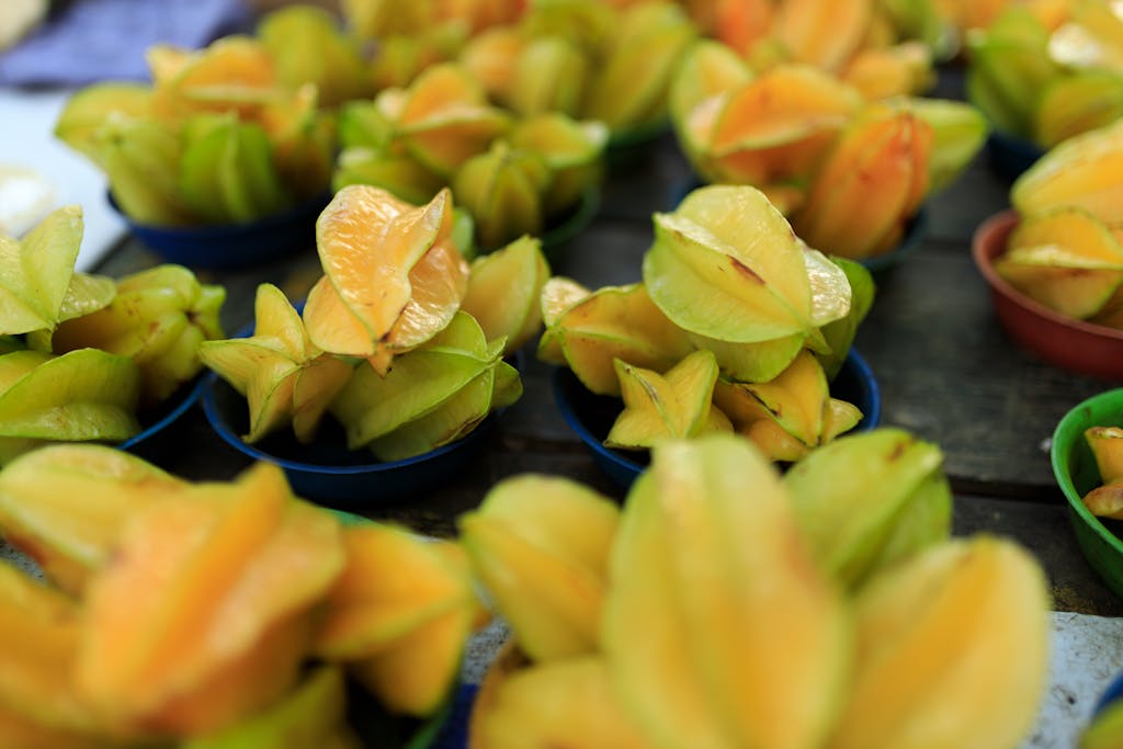 A vibrant display of fresh starfruit at an outdoor market, showcasing the tropical fruit's unique shape and color.
