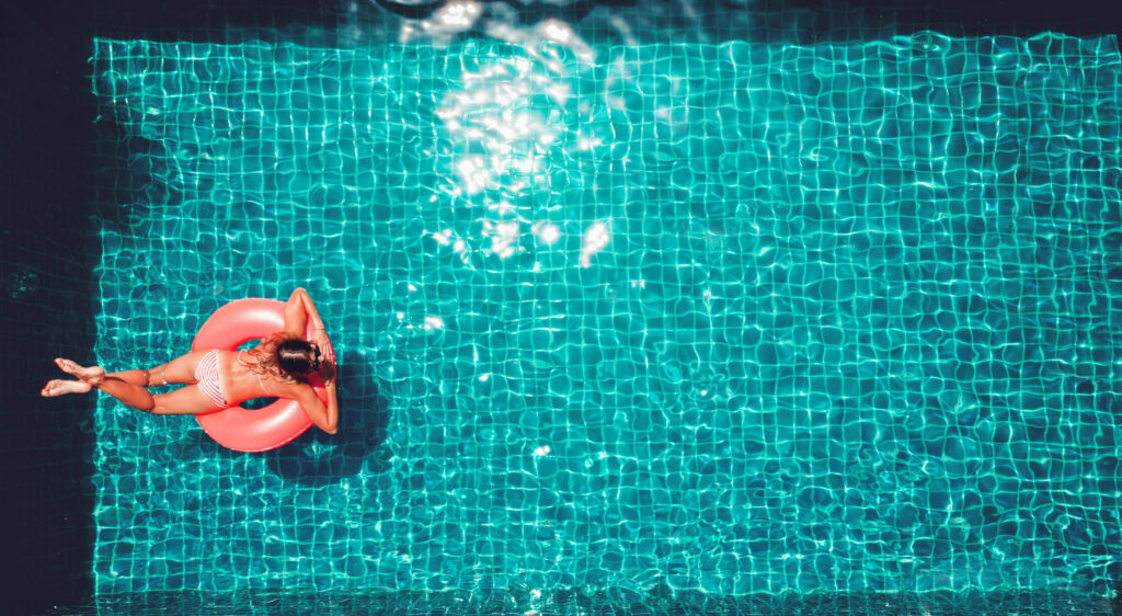 Young pretty slim woman on a pink air ring in the swimming pool