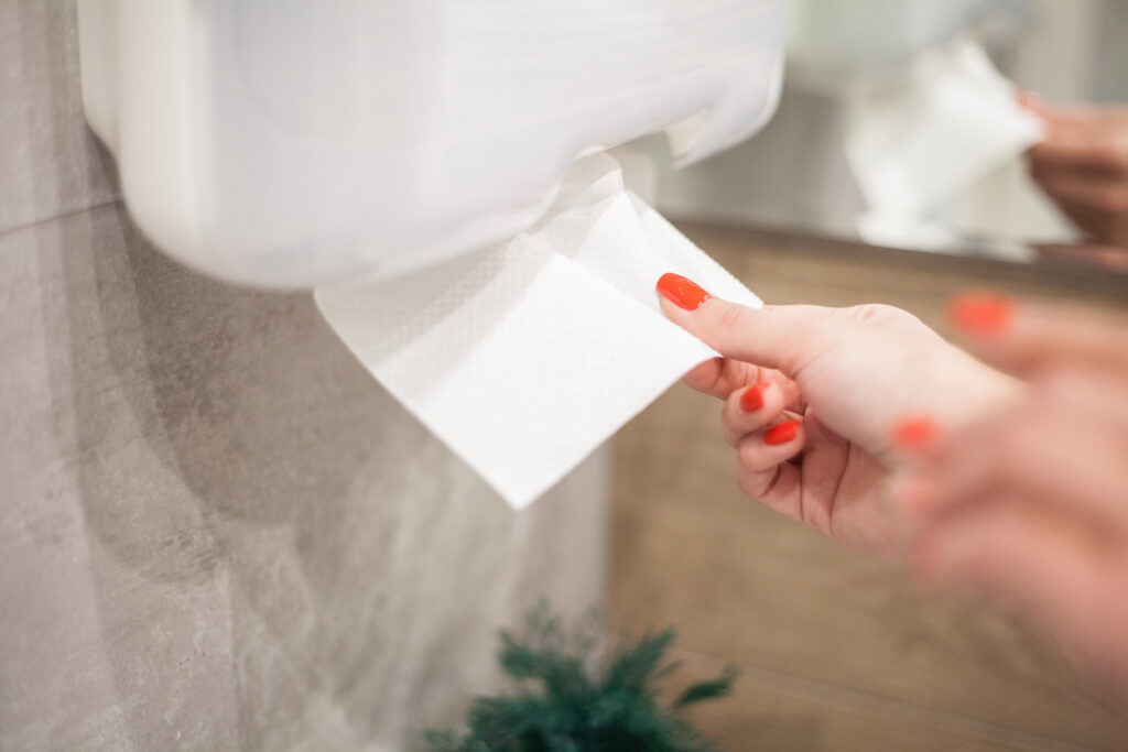 Paper towel dispenser. Hand of woman takes paper towel in 