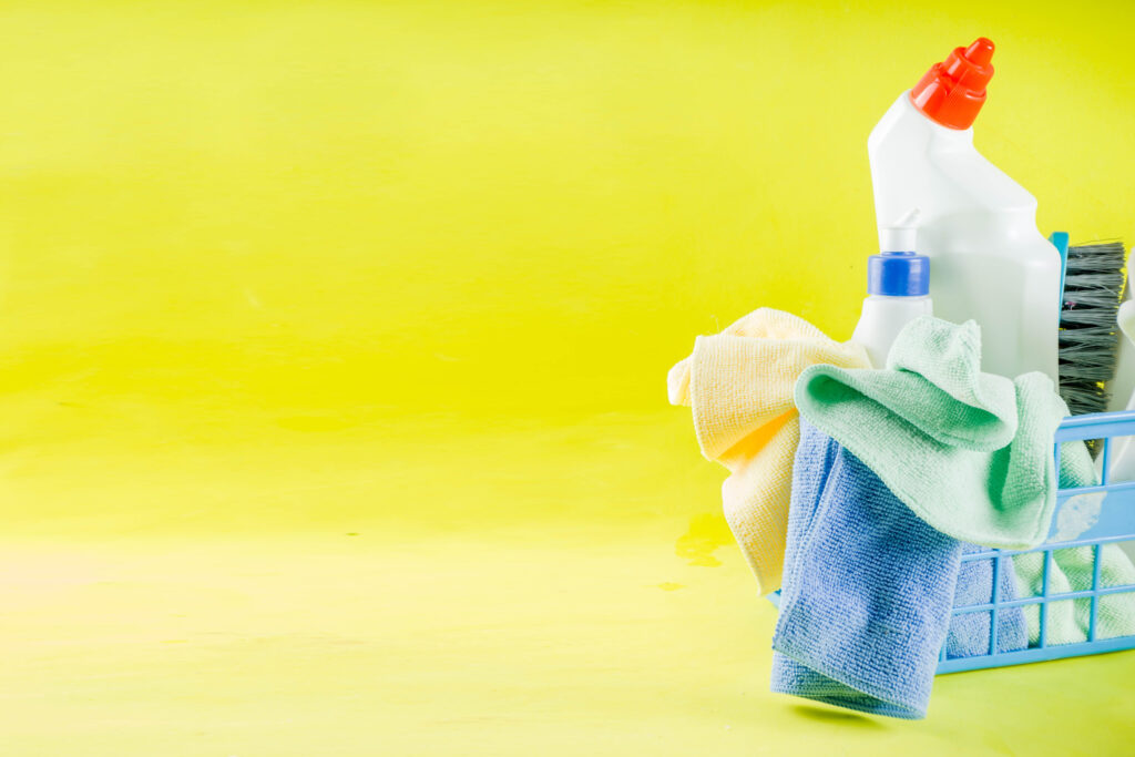 Cleaning concept with different cleaning supplies, on bright yellow background top view, copy space