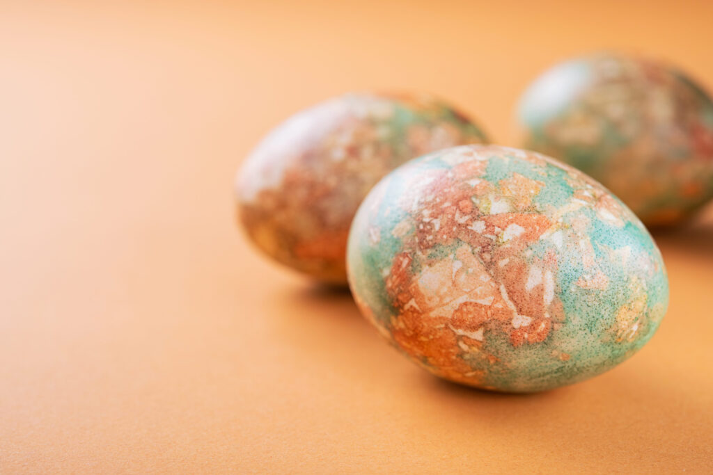 Marble painted easter eggs with flowers on orange background. copyspace for text