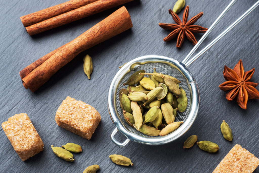 Whole grains of cardamom, a stick of cinnamon star anise and cane sugar. Close up. Ingredients for making the Indian drink masala tea