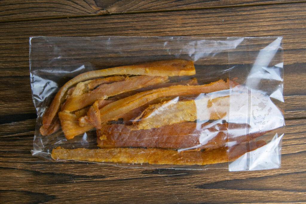 Peruvian squid in a transparent package on wooden background. Snack on fish with beer. Close-up.