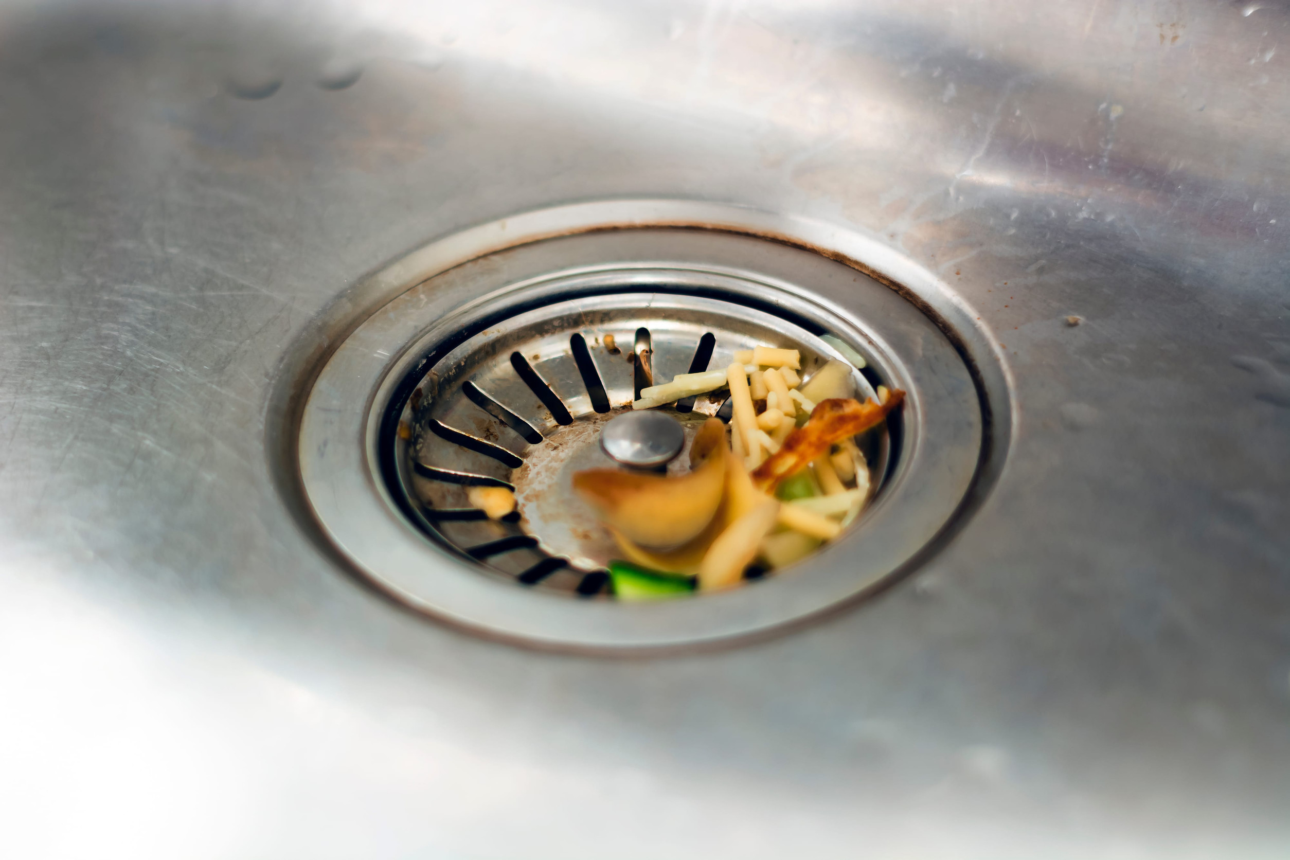 the leftovers of food left inside the kitchen sink are about to clog the drain. Food waste. Food leftovers that are compostable and reusable