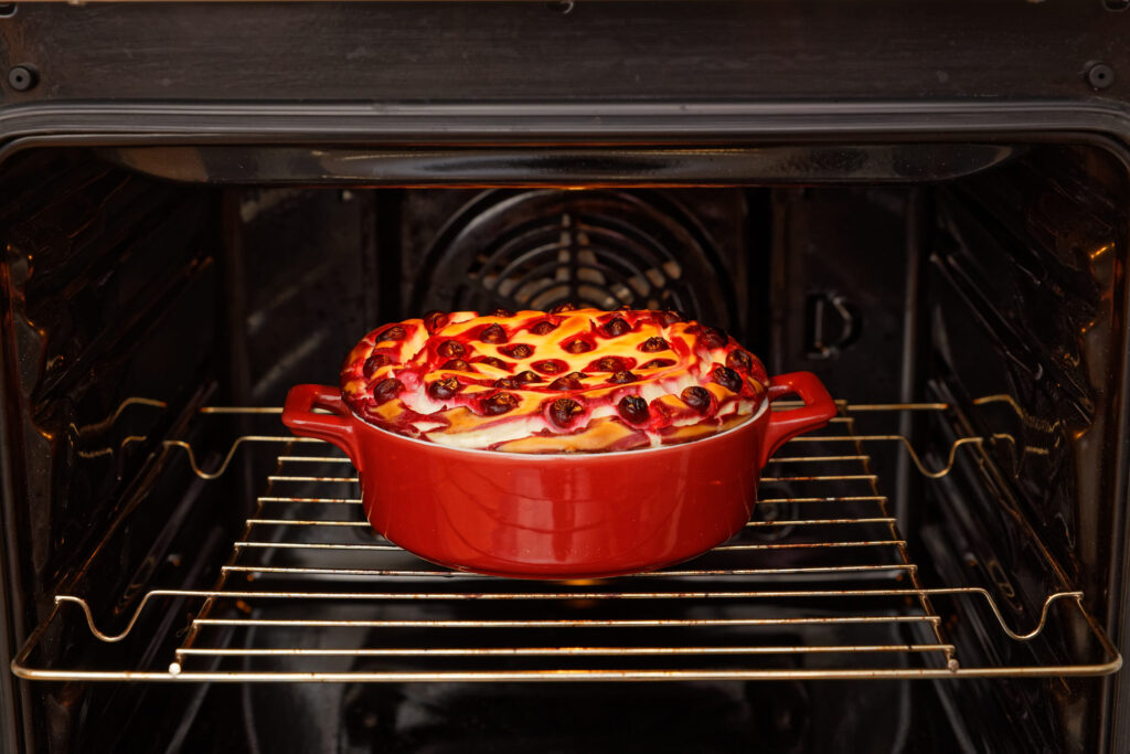 Homemade pastry.  Cottage cheese and cherry cheesecake in red ceramic bow cooked in the domestic oven. Shallow focus.