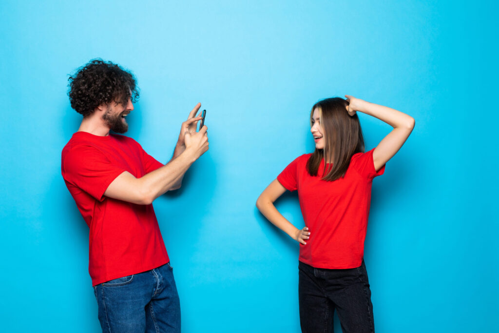 Beautiful couple making a photo with phone on blue background