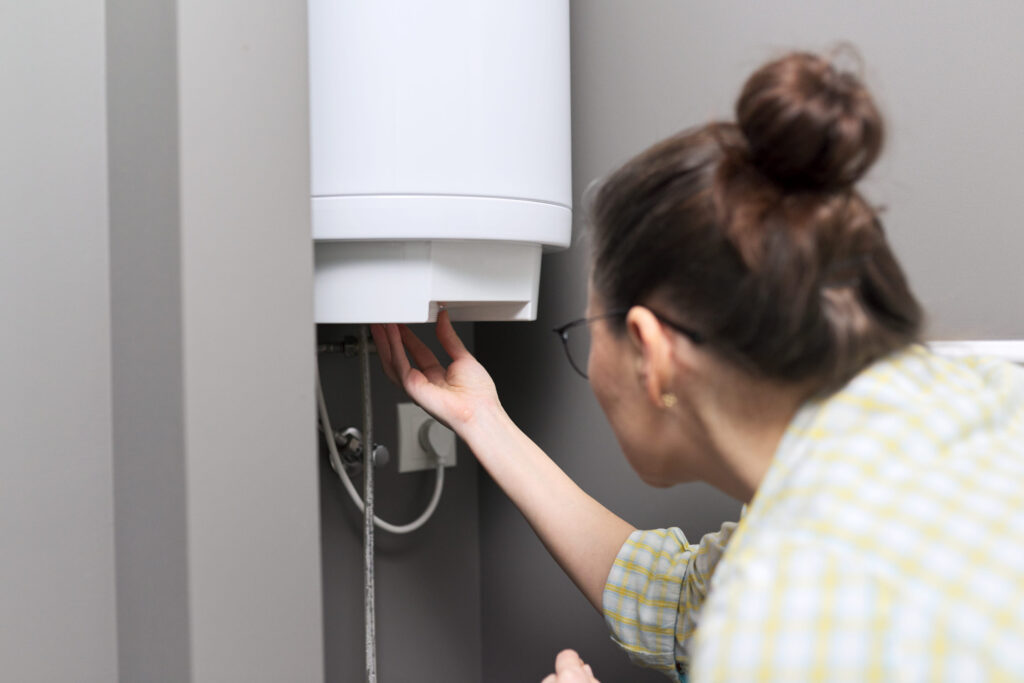 7 Household Appliances Secretly Bleeding You Dry Through Water Waste 3 Home water heater, a woman regulates the temperature on an electric water heater, comfort and hot water in the house