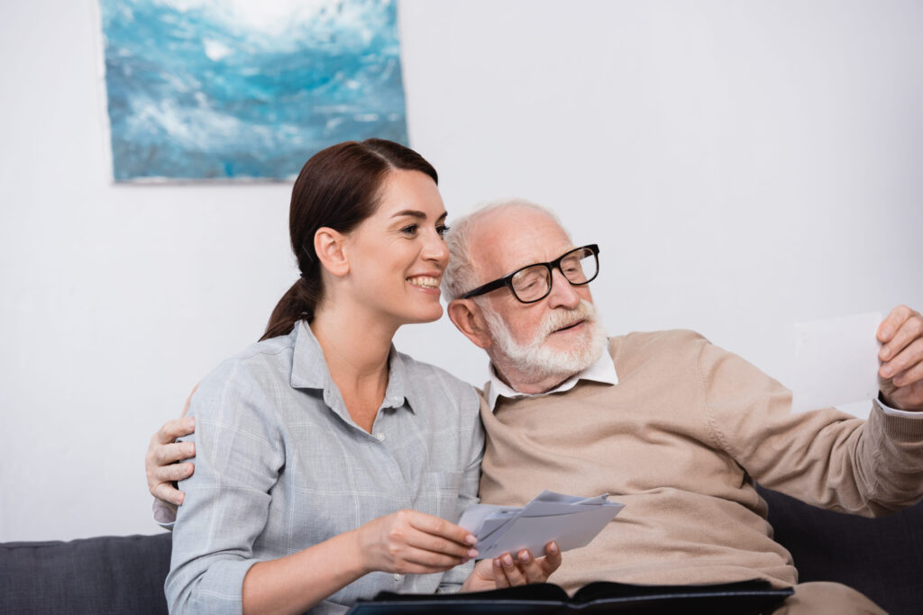 happy woman with aged father looking at family photos together