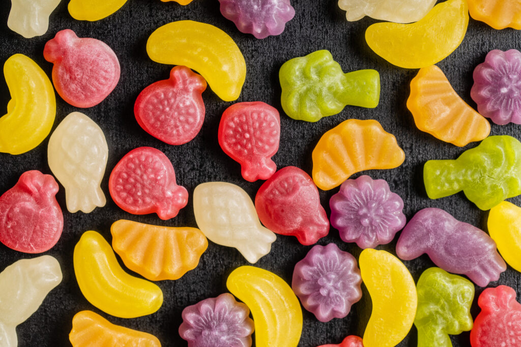 Colorful fruity jelly candies on black table. Top view.