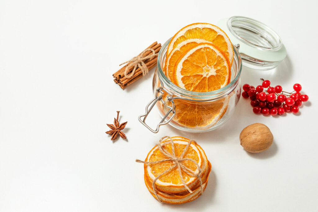 Creative, Christmas and new year, winter composition. dried orange slices in a glass jar, walnuts, viburnum berries and cinnamon sticks on a white background. copy space. selective focus