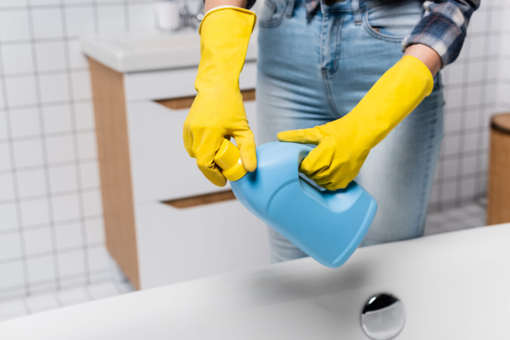 6 Worst Places You Should Never Keep Your Phone 2 Cropped view of woman in rubber gloves opening bottle of cleaner near bathtub