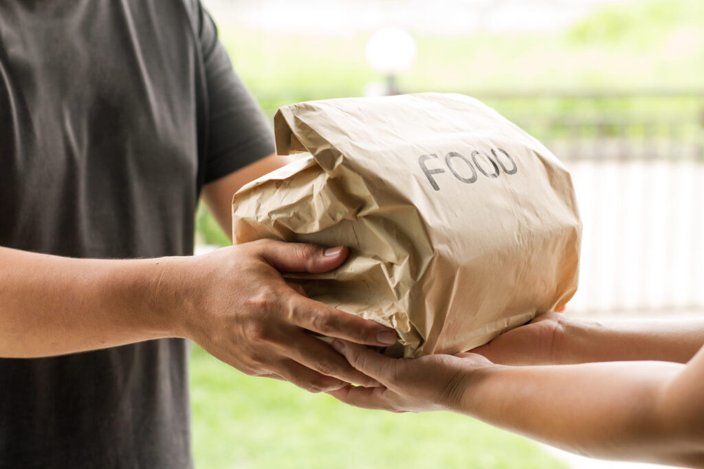 Asian delivery man sending a food box to customer at home