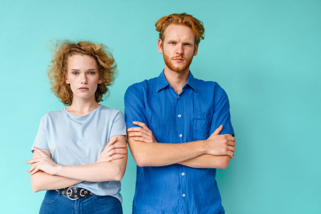 Portrait of a beautiful serious youngcouple standing isolated over blue background