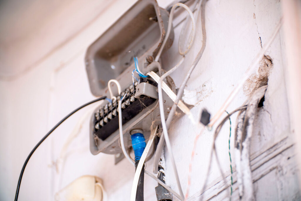 An old junction box with wires on a light wall. Selective Focus