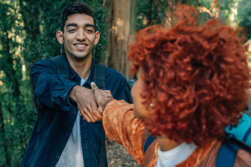 young people holding hands helping each other hiking