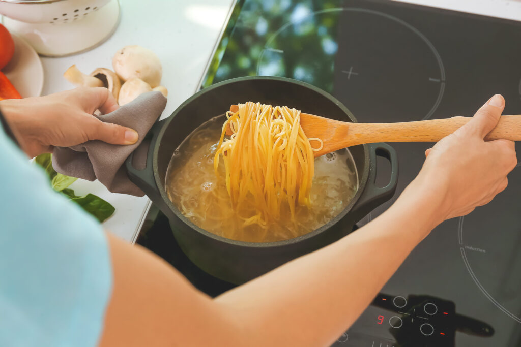 Woman cooking pasta on electric stove