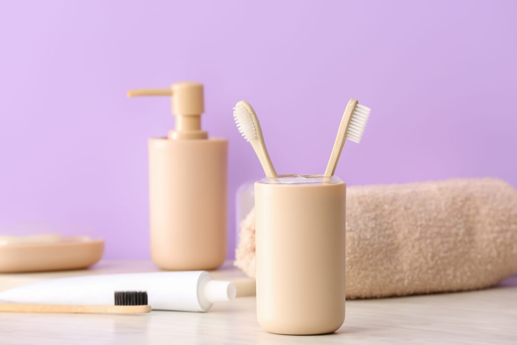 Holder with wooden toothbrushes and toothpaste on table in bathroom