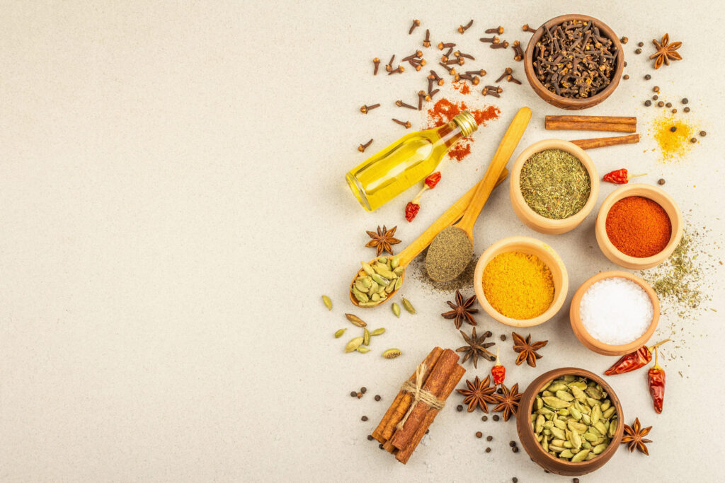 A set of spices for cooking curry. Aromatic condiments: turmeric, paprika, cardamom, cinnamon, star anise, chili, black pepper, dry herbs, salt. Light stone concrete background, top view