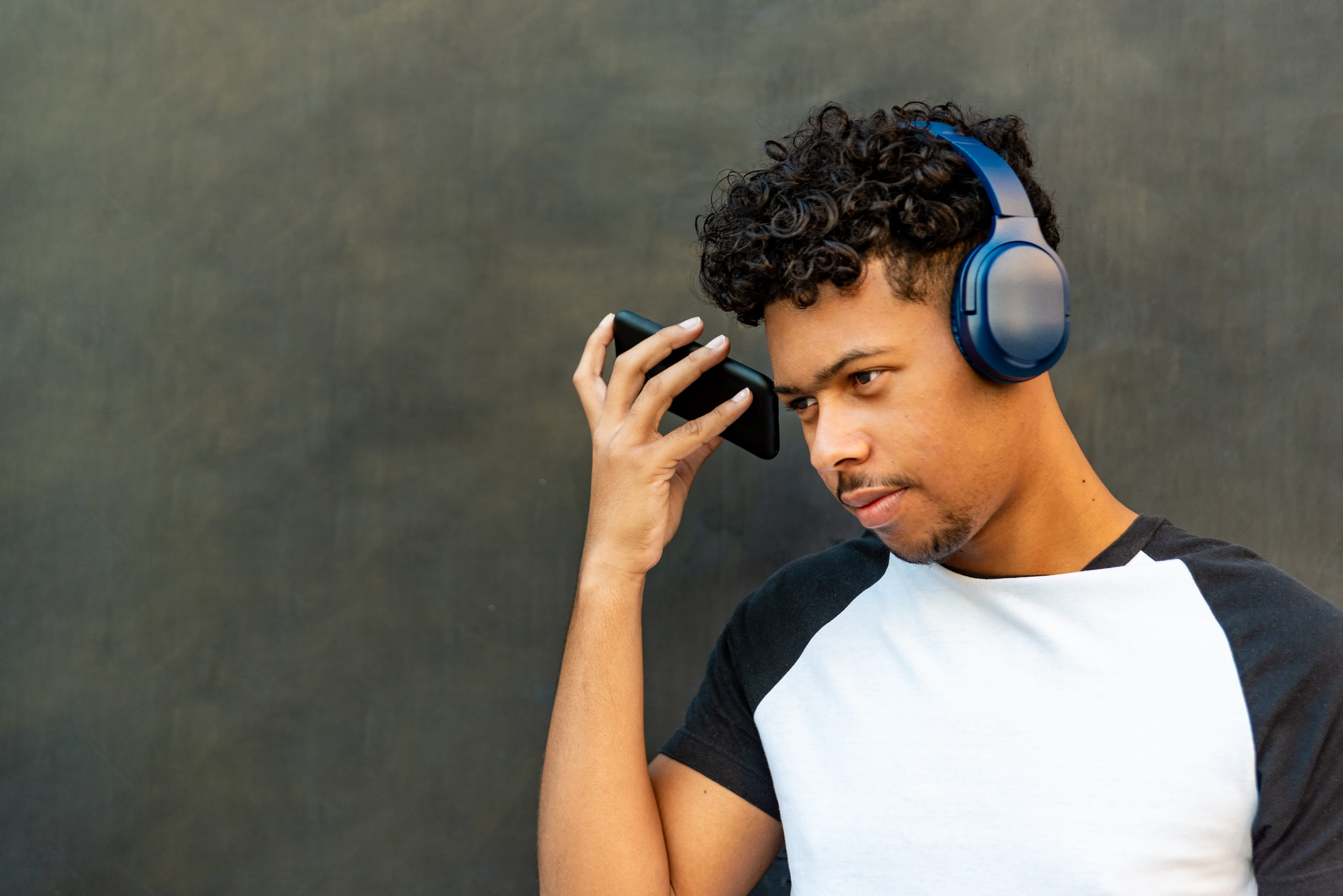 Afro latin young man listening to music against a wall