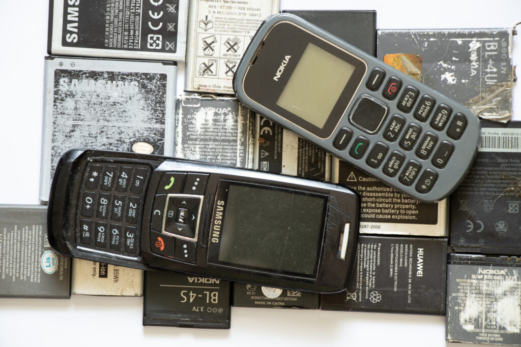Ukraine Dnipro 10.08.2021 - on a white paper background there are phones of different models and different generations and brands next to batteries, many different phones and batteries
