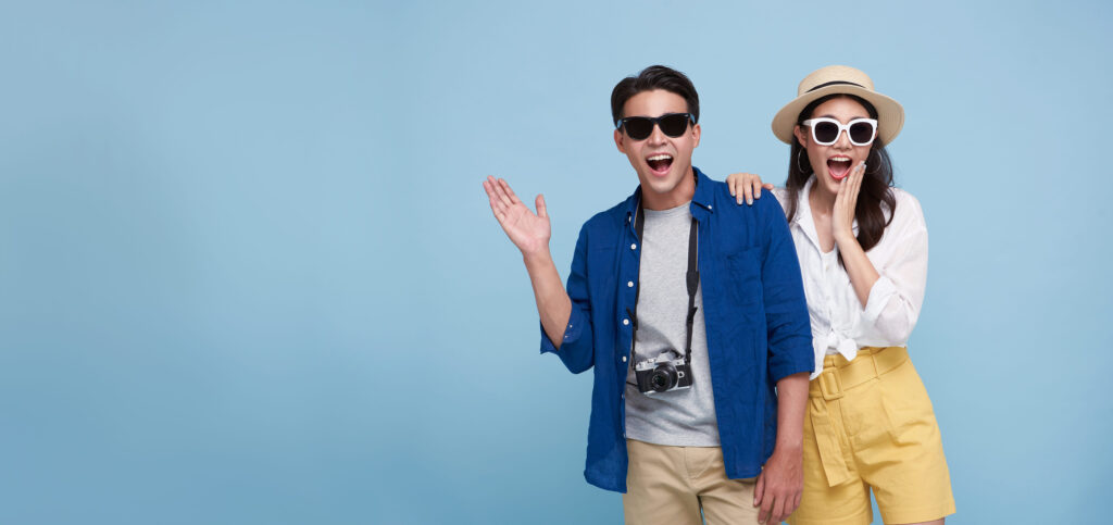 Excited Asian couple tourist dressed in summer clothes to travel on holidays isolated on blue copy space background.