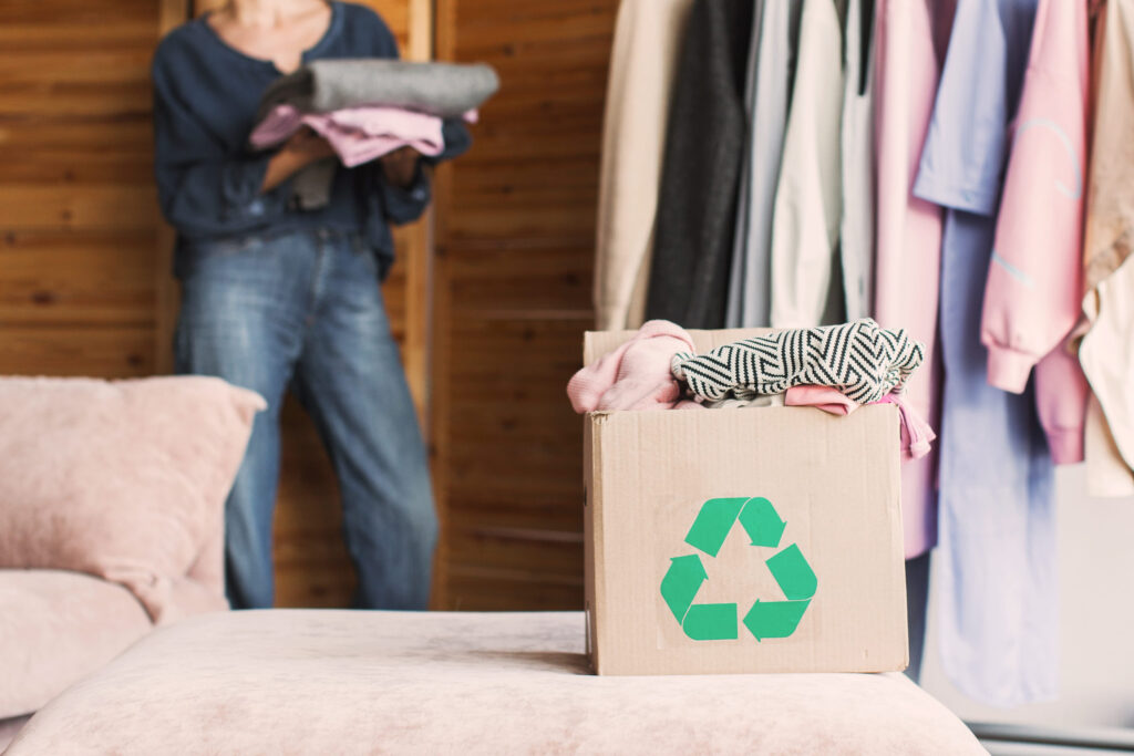 Female put stack things clothes in cardboard recycle box, recycle concept