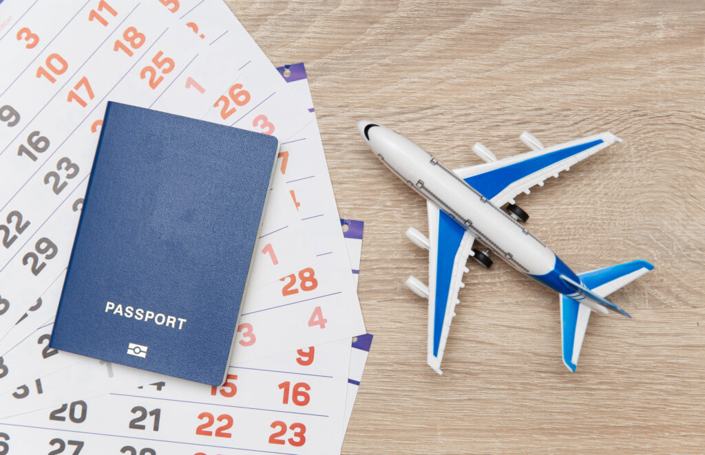 Paper Calendar with air plane and passport on table. Travel concept. Top view