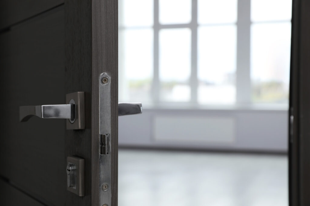 Wooden door open into empty office room, closeup. Space for text