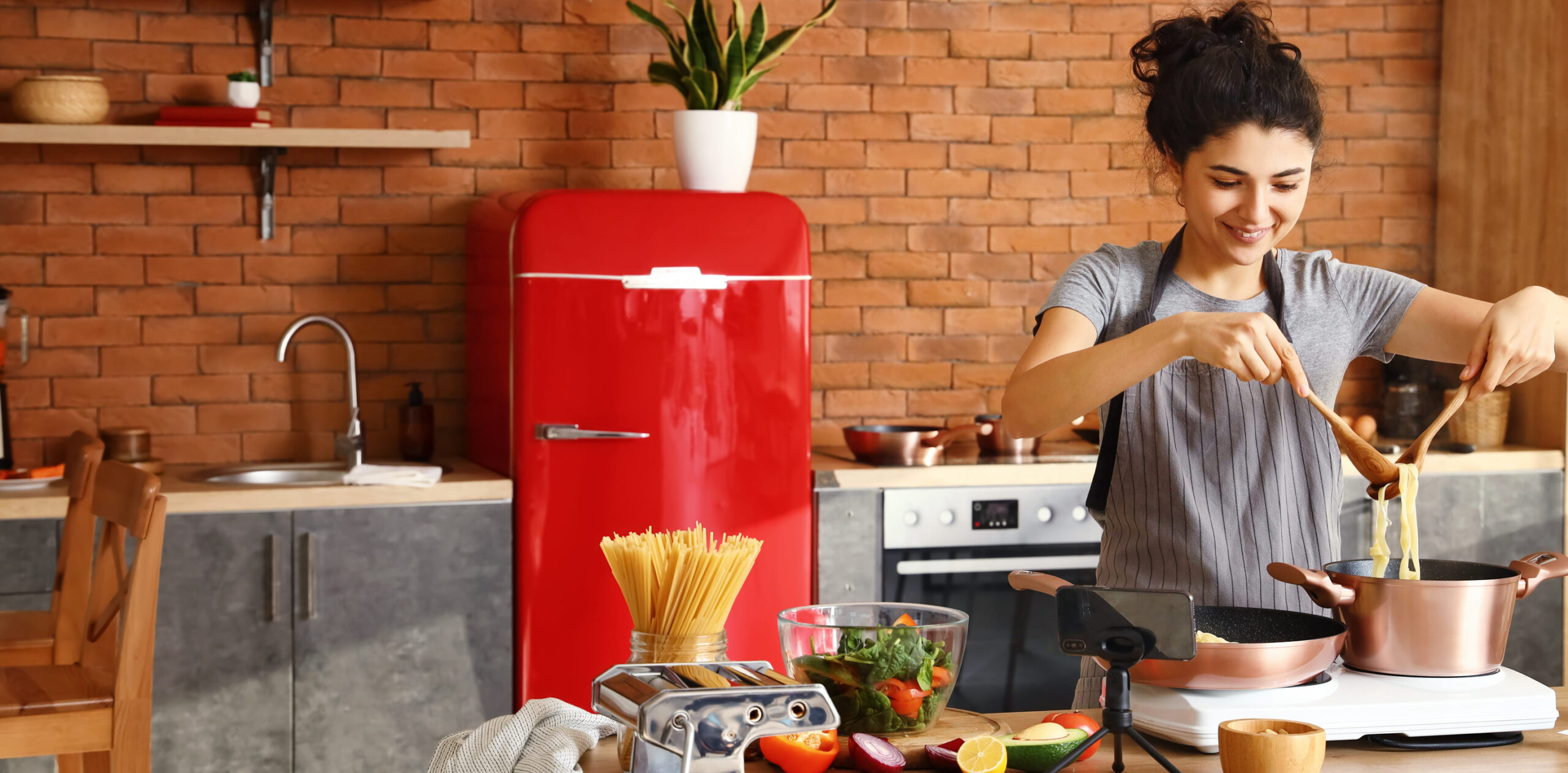 Young female blogger recording video while cooking in kitchen