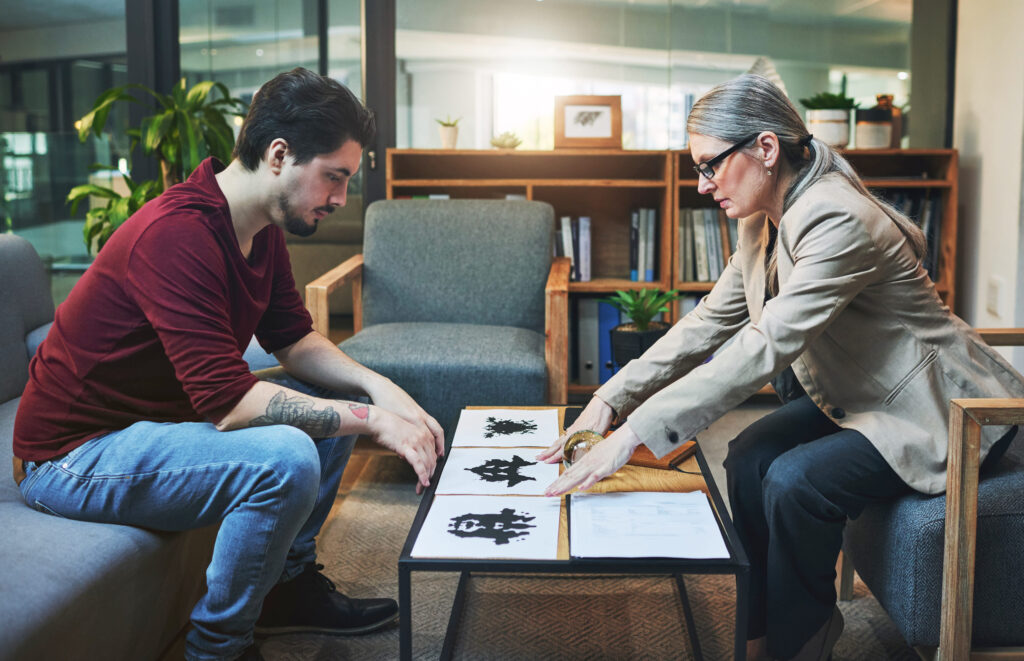 An ink pattern that determines your thought pattern. a mature psychologist conducting an inkblot test with her patient during a therapeutic session.