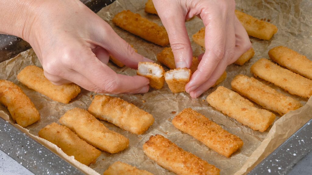 Baking pan with fish sticks close up on the kitchen table. Crunchy delicious lightly breaded with  bread crumbs fish sticks close-up