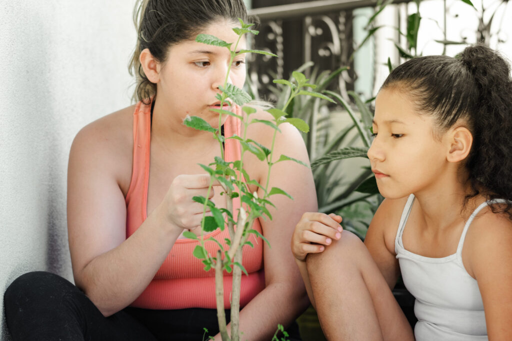 close-up of a young Latina mother with her young daughter teaching her how to take care of plants