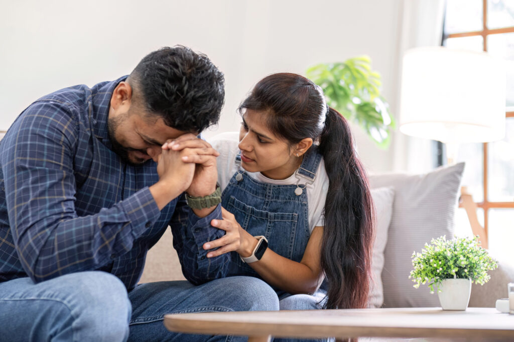 A young woman encourages and holds the hand of her worried husband. is having a hard time making some decisions.