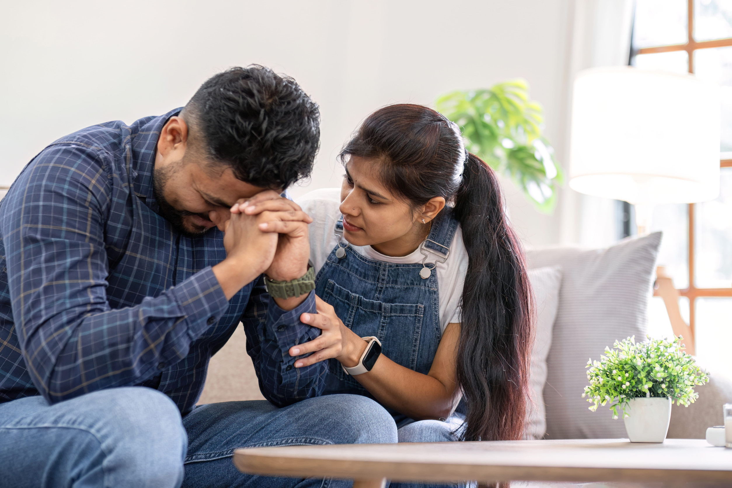 A young woman encourages and holds the hand of her worried husband. is having a hard time making some decisions.