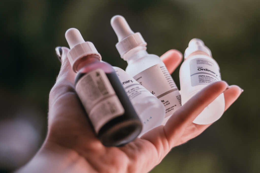 Closeup of female hands holding cosmetic serum jars for skincare.