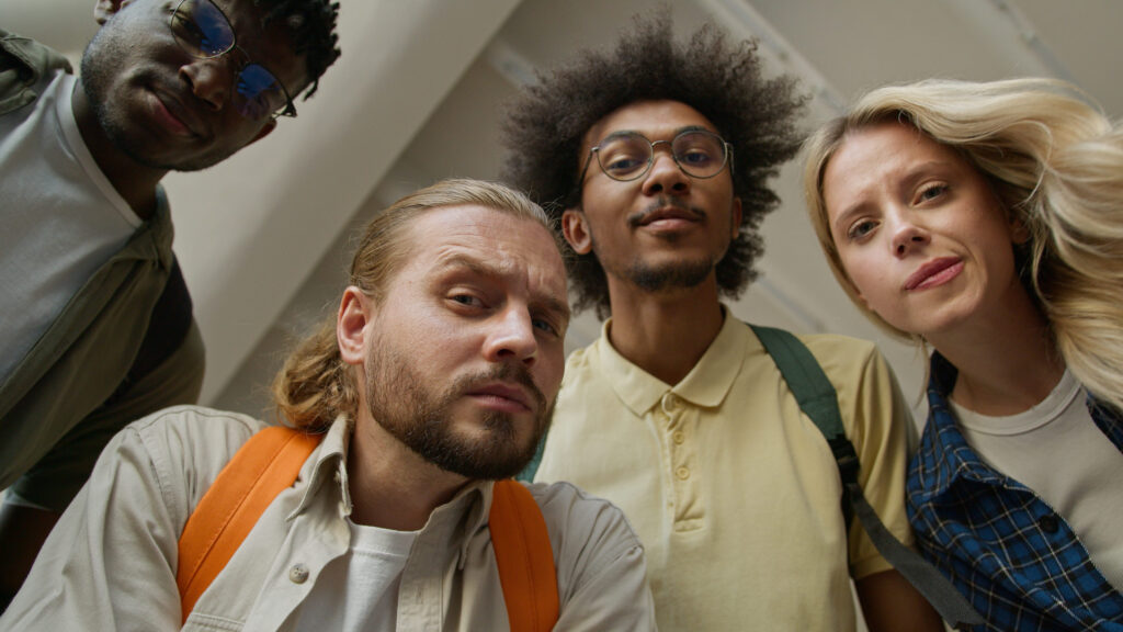 Bottom view university college four students confused interested puzzled amazed multiracial friends male men Caucasian African American guys woman girl female looking at camera unexpected education