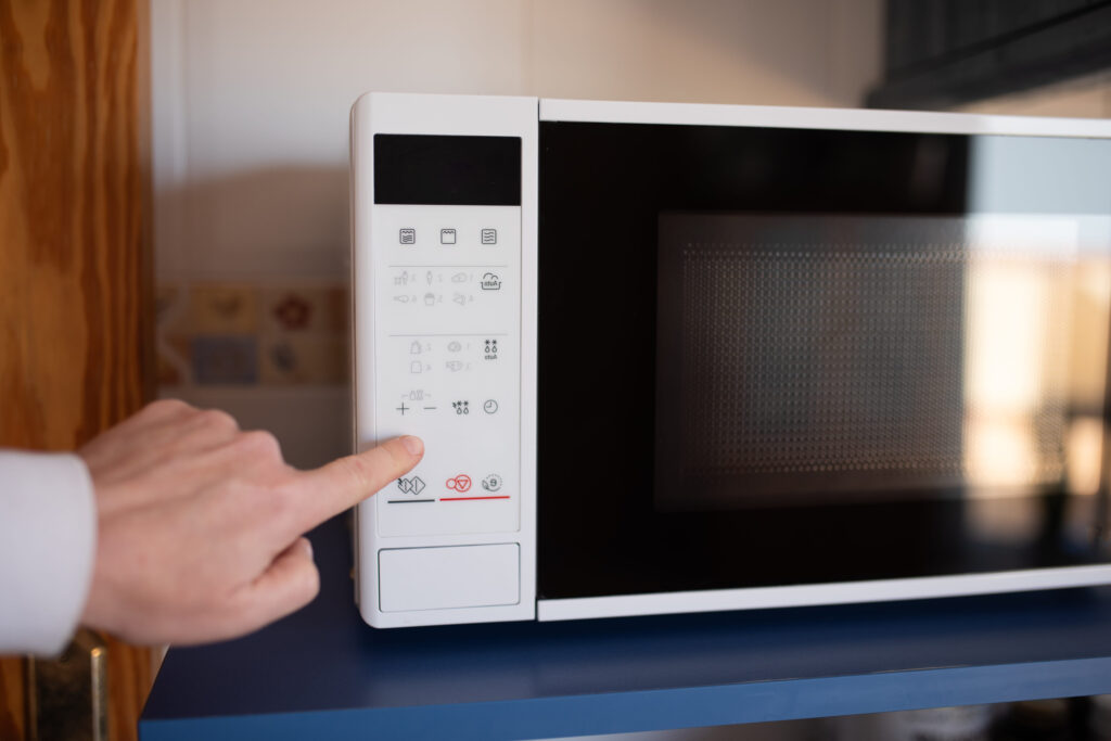 User adjusting settings on white microwave oven in kitchen interior