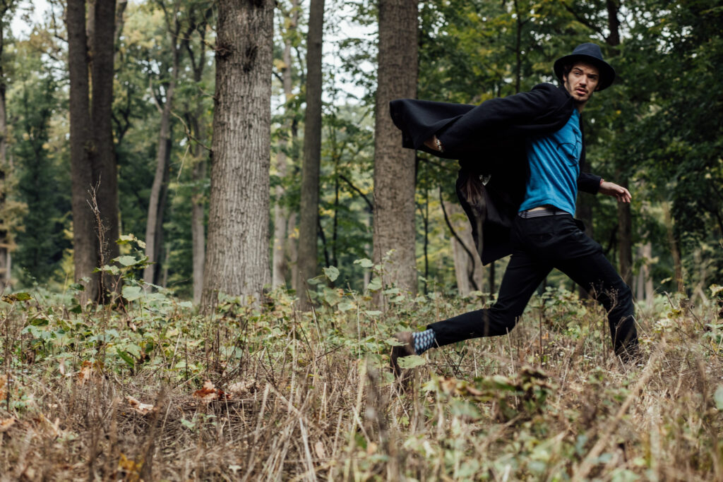 young man with black hat walkink in forest