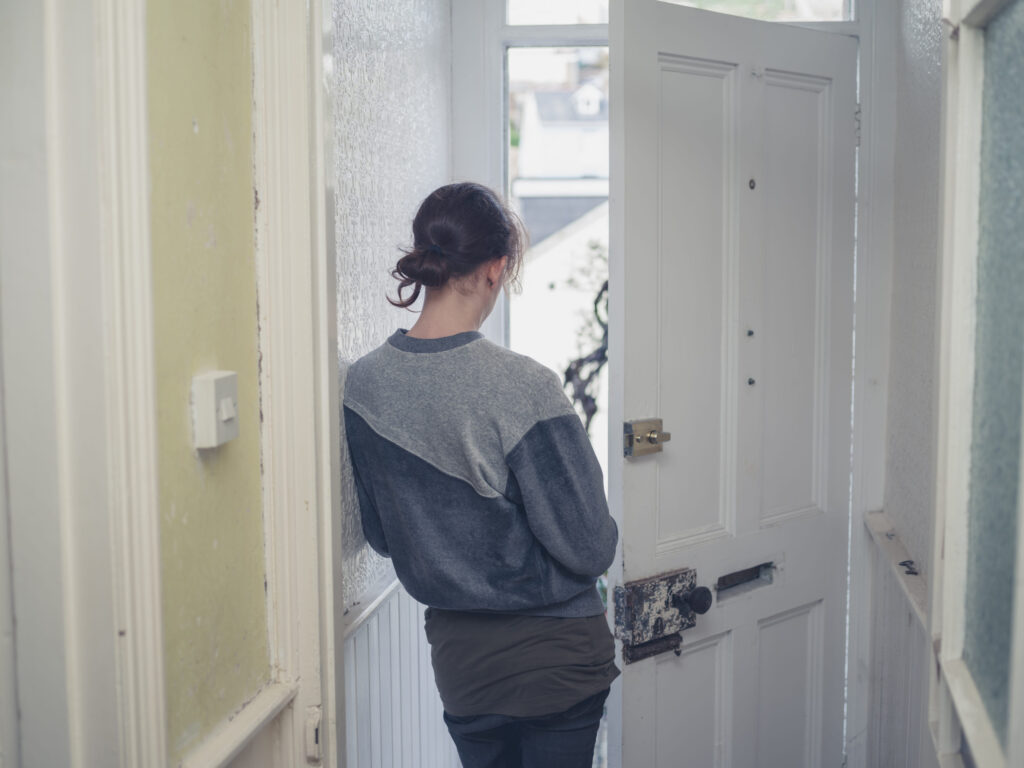 A young woman is standing in a doorway at home
