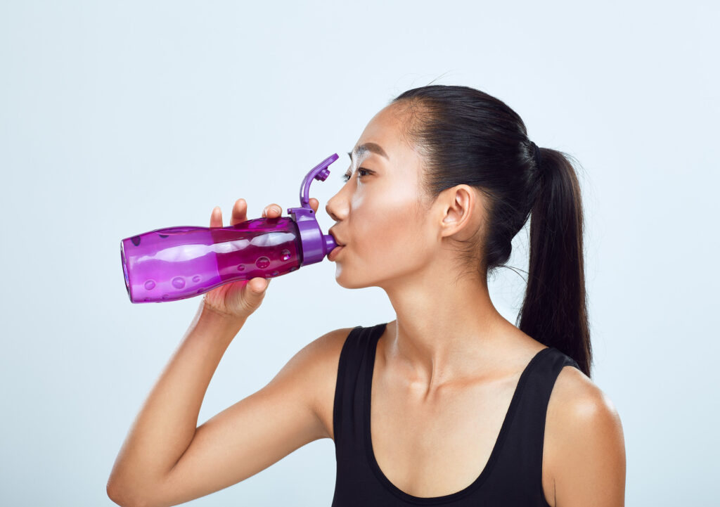 Young sports woman drinks bottled water. Sports lifestyle, fluid replenishment