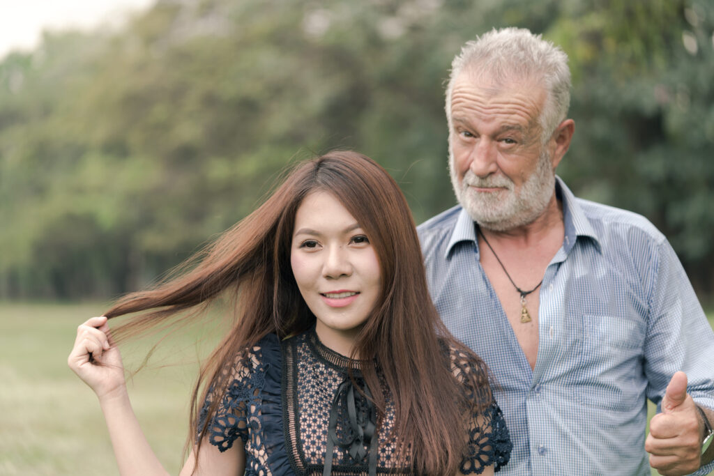 Grand father and beautiful young girl smile and stroll in the garden.