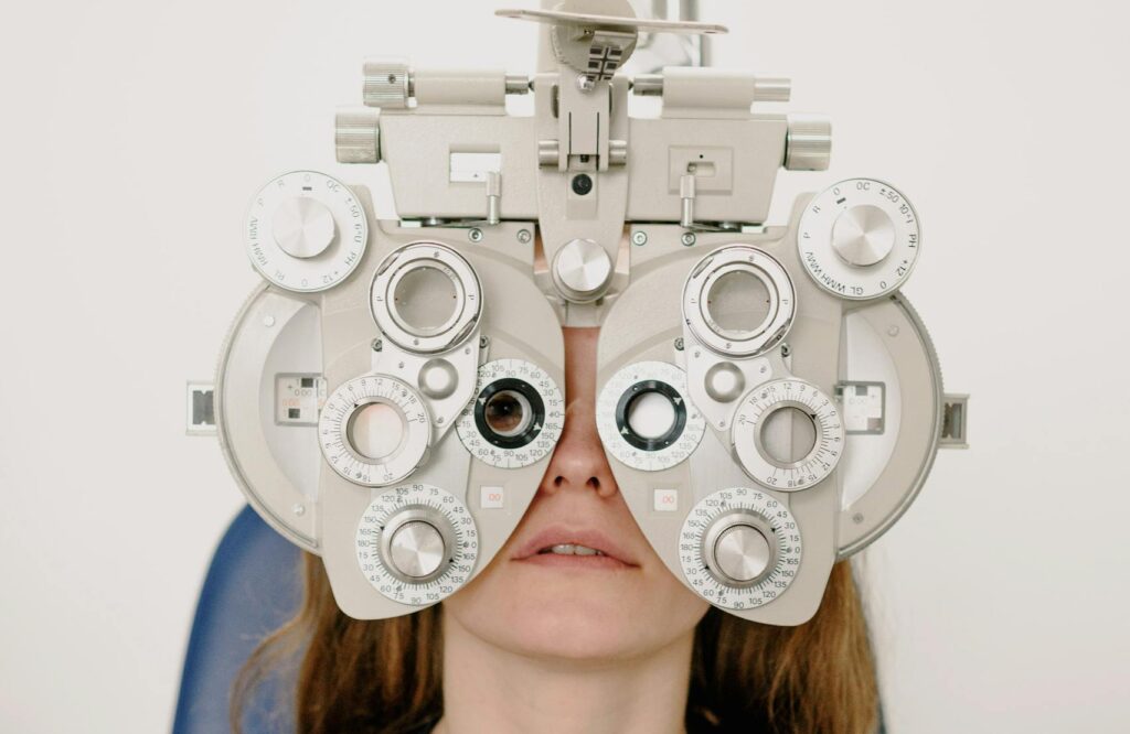 A Caucasian woman undergoing a vision test using a phoropter in a clinic.