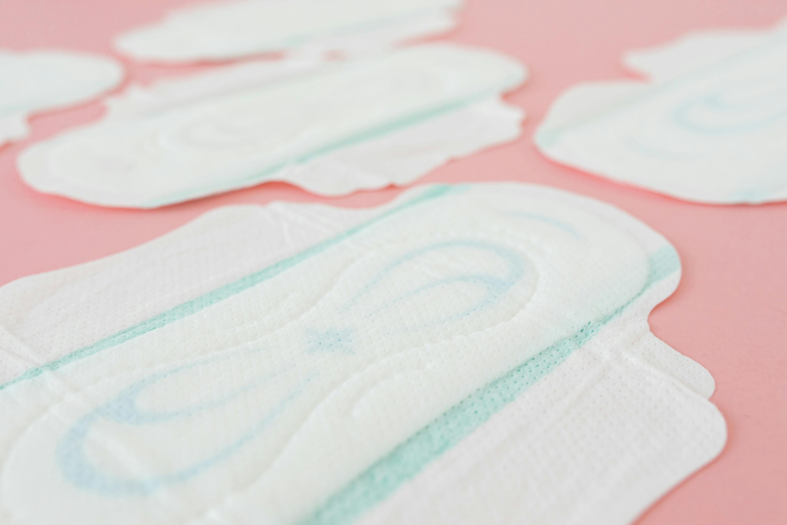 A close-up image of white menstrual pads arranged on a soft pink background, perfect for feminine health and hygiene themes.