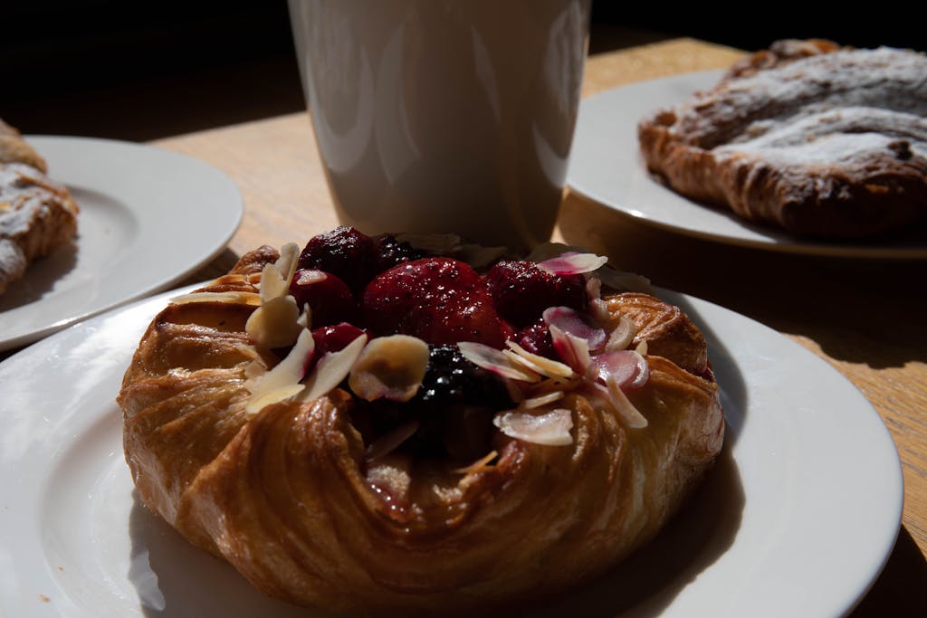 A close-up of a delicious berry danish pastry topped with almonds on a sunny morning.