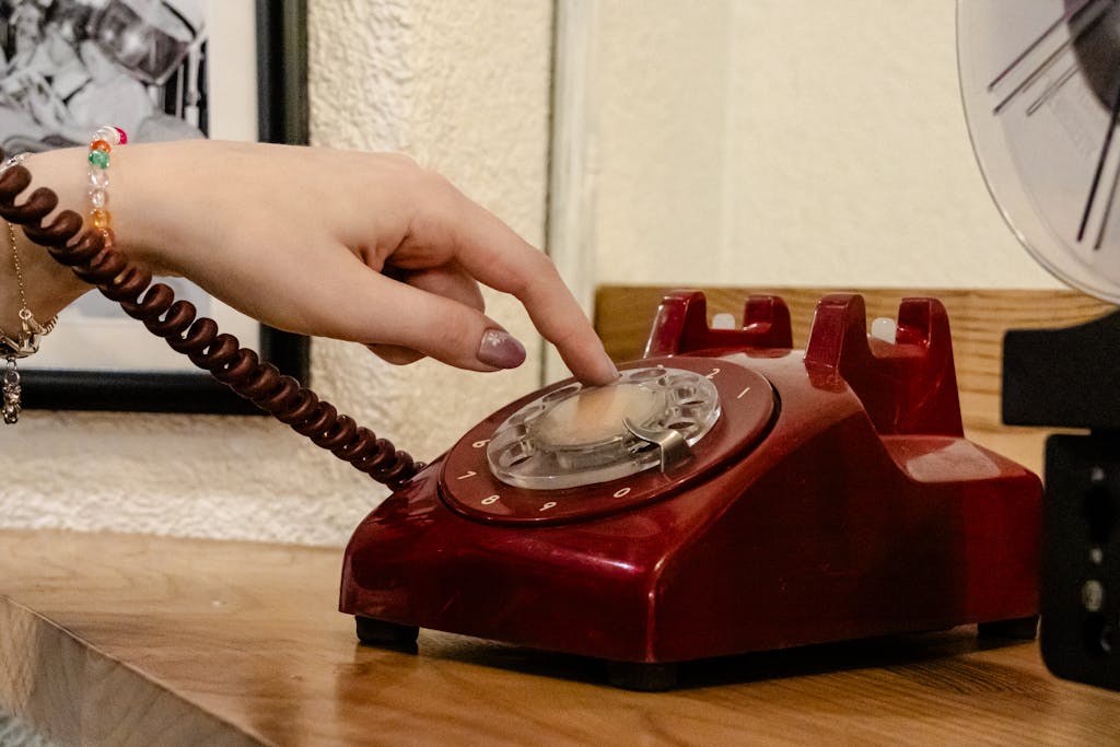 8 Things Baby Boomers Had That the Modern World Destroyed 4 A close-up of a hand dialing a classic red rotary phone, capturing nostalgia.