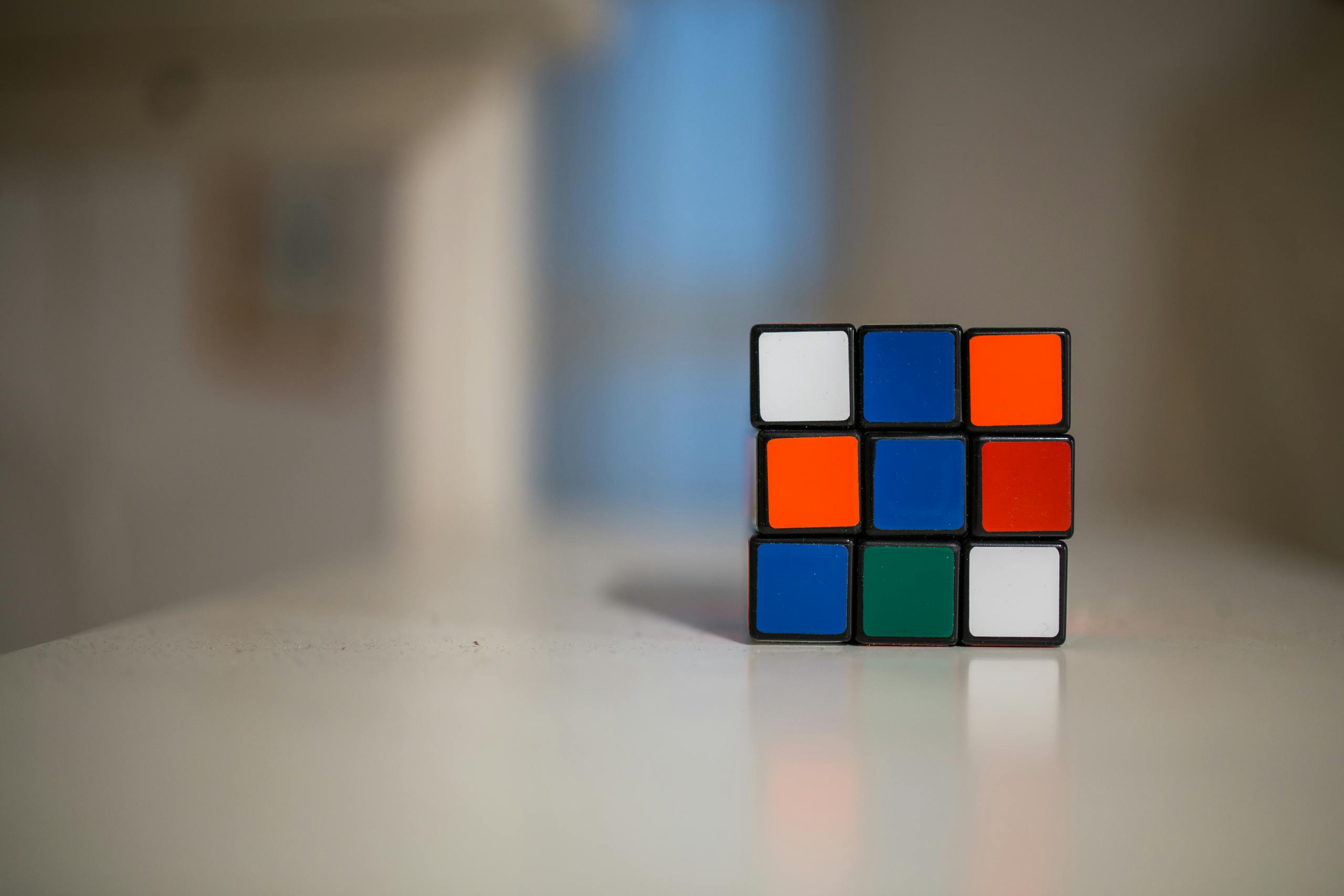 A close-up of a partially solved Rubik's Cube on a white table indoors.